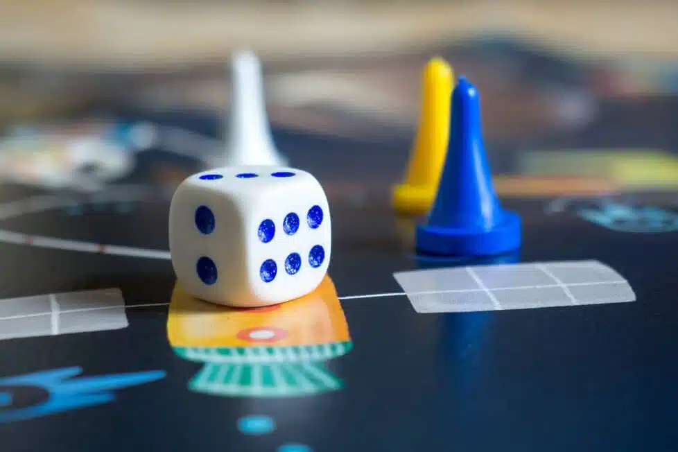 Dado y fichas sobre un juego de mesa educativo