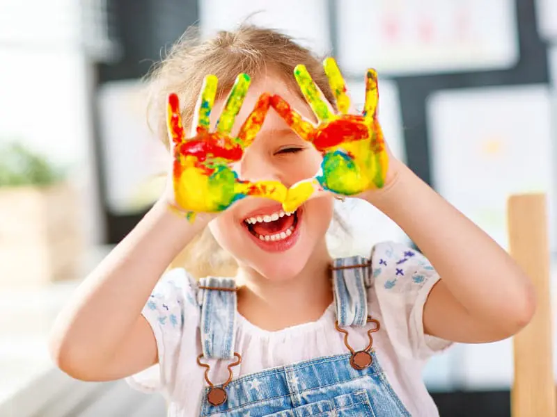 Niña sonriente con las manos pintadas en un taller de creatividad
